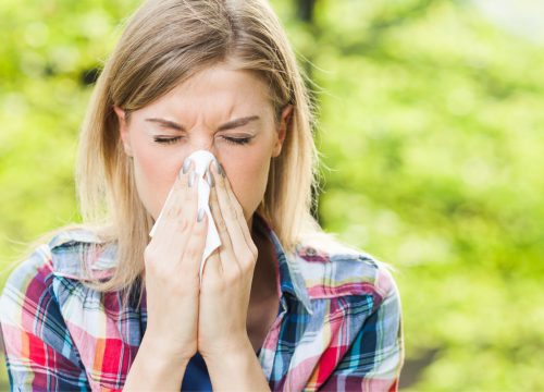 Woman with allergies sneezing into a tissue